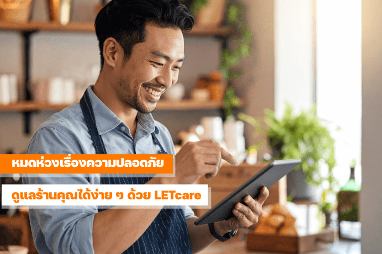 เจ้าของร้าน SME ยิ้มขณะดูภาพจากกล้องวงจรปิด LETcare บนแท็บเล็ต ภายในร้านค้าที่อบอุ่นและปลอดภัย
